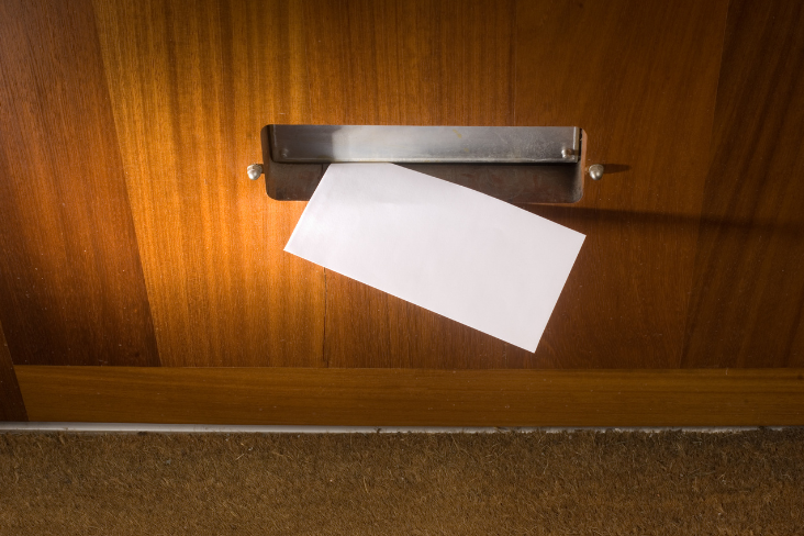 An envelope pushed through a door An envelope pushed through a door