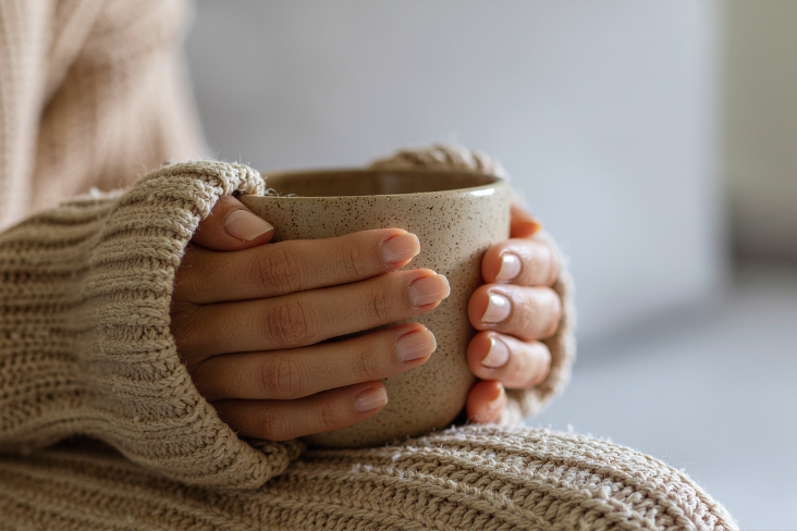 Person in a cardigan holding a mug