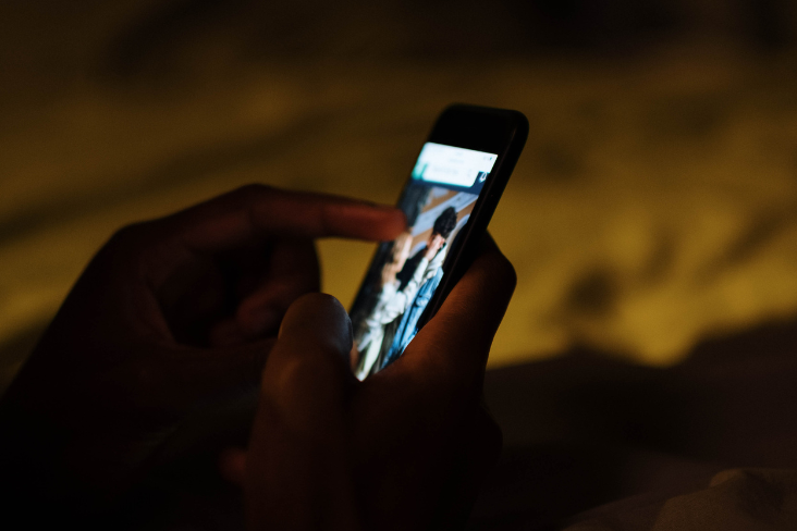 Person tapping a phone with an image of two people displayed Person tapping a phone with an image of two people displayed